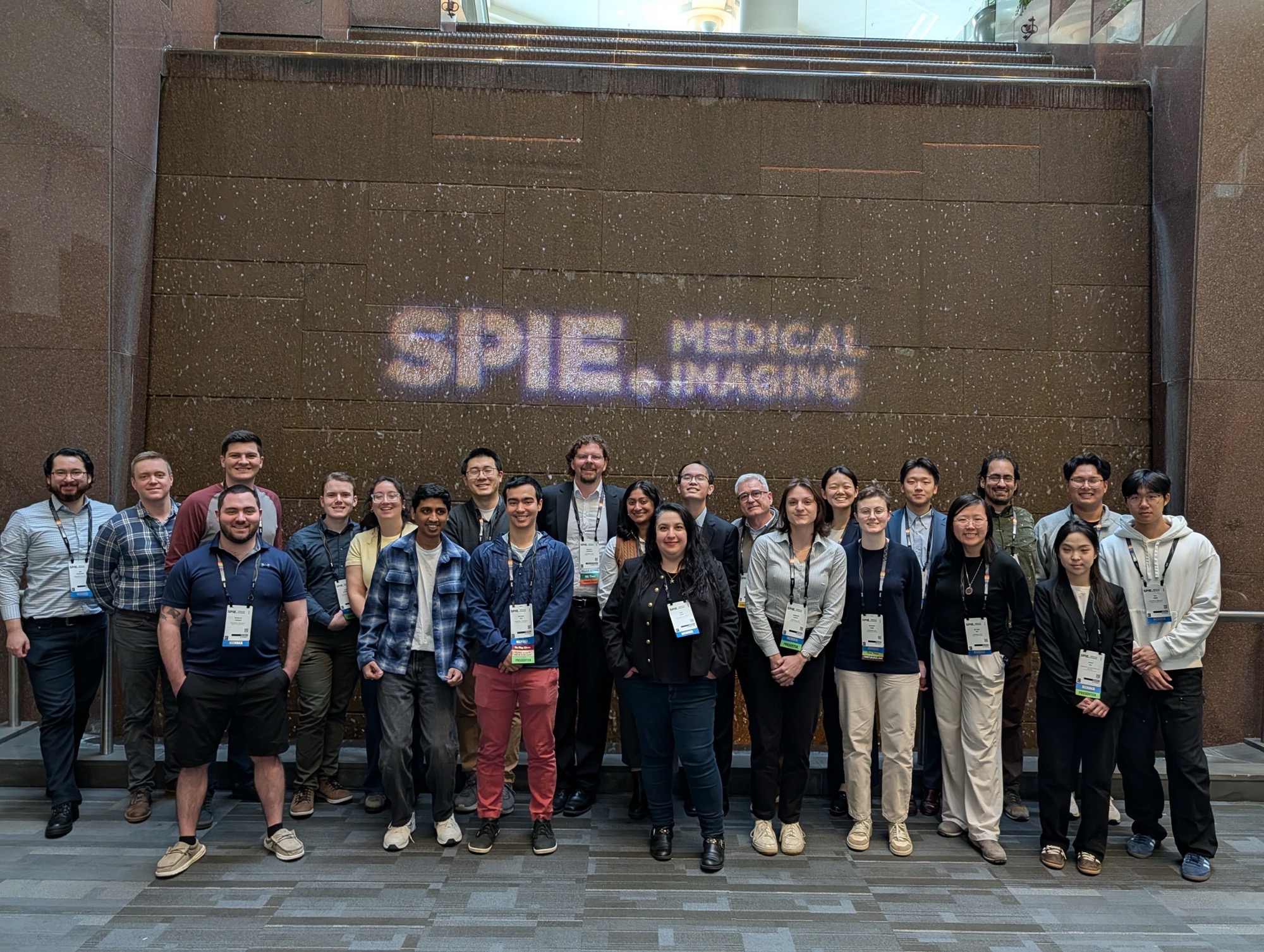 A group photo of many Vanderbilt attendees in front of a waterfall marked with SPIE Medical Imaging 
